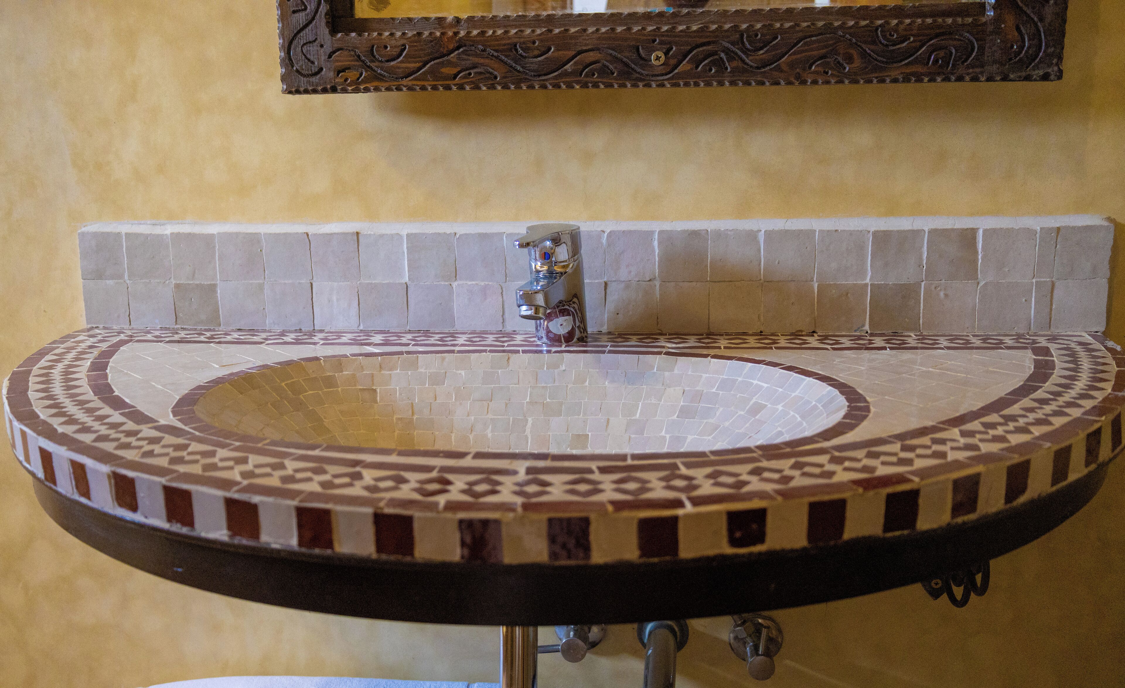 A bathroom with a round sink, tiled backsplash, and a mirror above it.