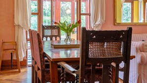 Un coin repas avec une table en bois, des chaises et un vase rempli de fleurs.