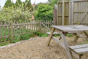 Eine Holzterrasse mit Picknicktisch, umgeben von einem Holzzaun und Kiesgrund.