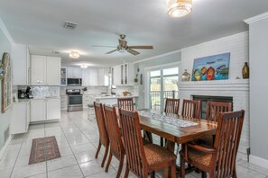 A modern kitchen with white cabinets, a dining area with wooden chairs, and a ceiling fan.