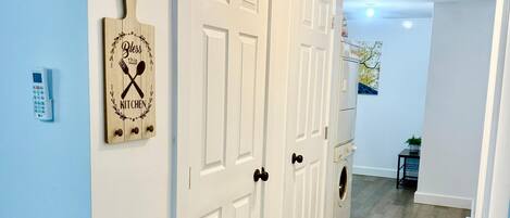 Un passadís amb portes blanques, un temporitzador de cuina i una làmpada penjant a la paret.
