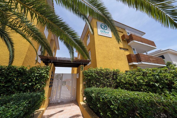 A yellow building with a sign reading "albir experience" and a gated entrance.