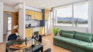 Un apartamento moderno con cocina, comedor y un sofá verde.