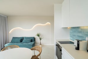 A modern living room with a sofa, a dining table, and a kitchen area with a toaster.