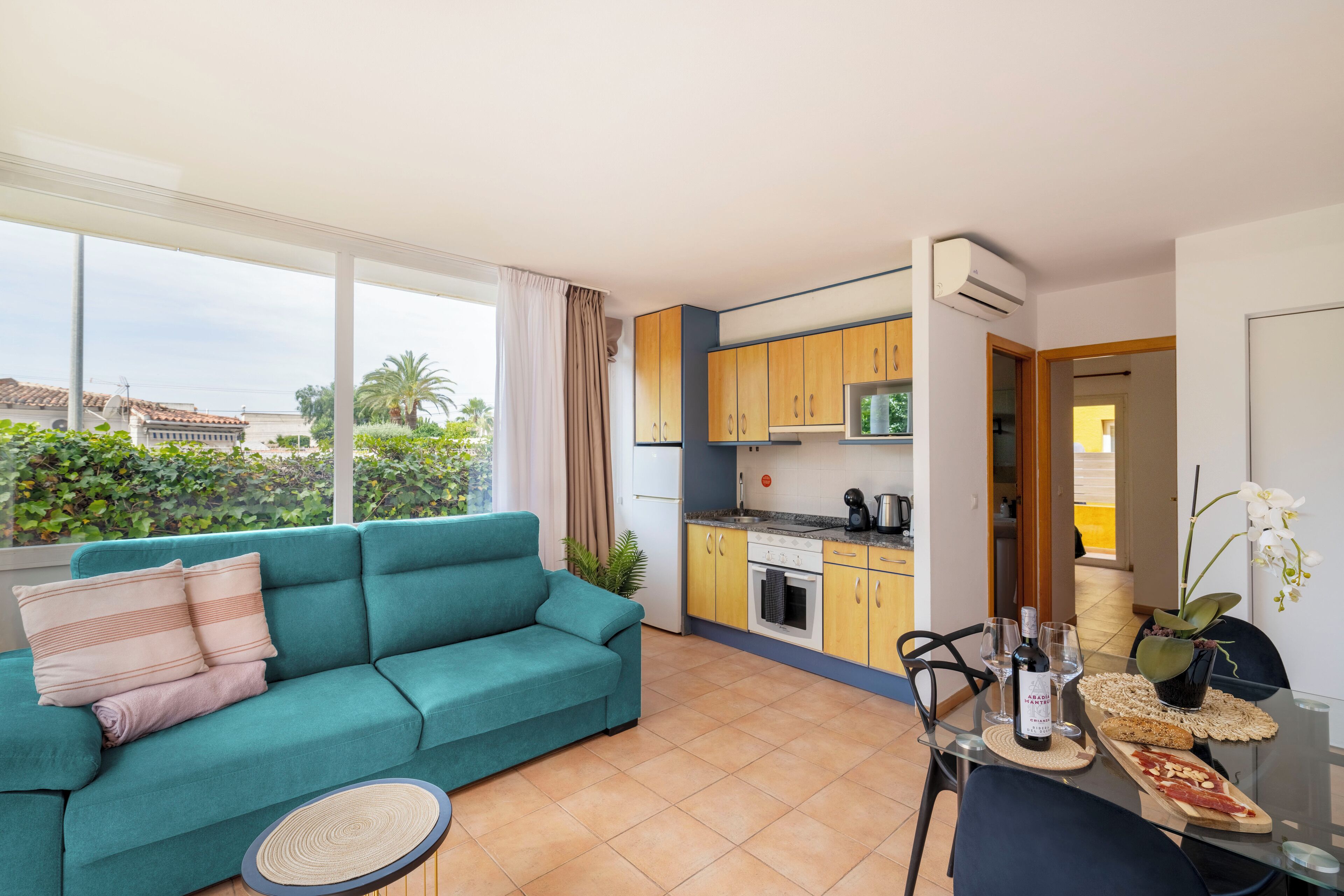 Un espacio habitable compacto con sofá, kitchenette y comedor con mesa para dos.