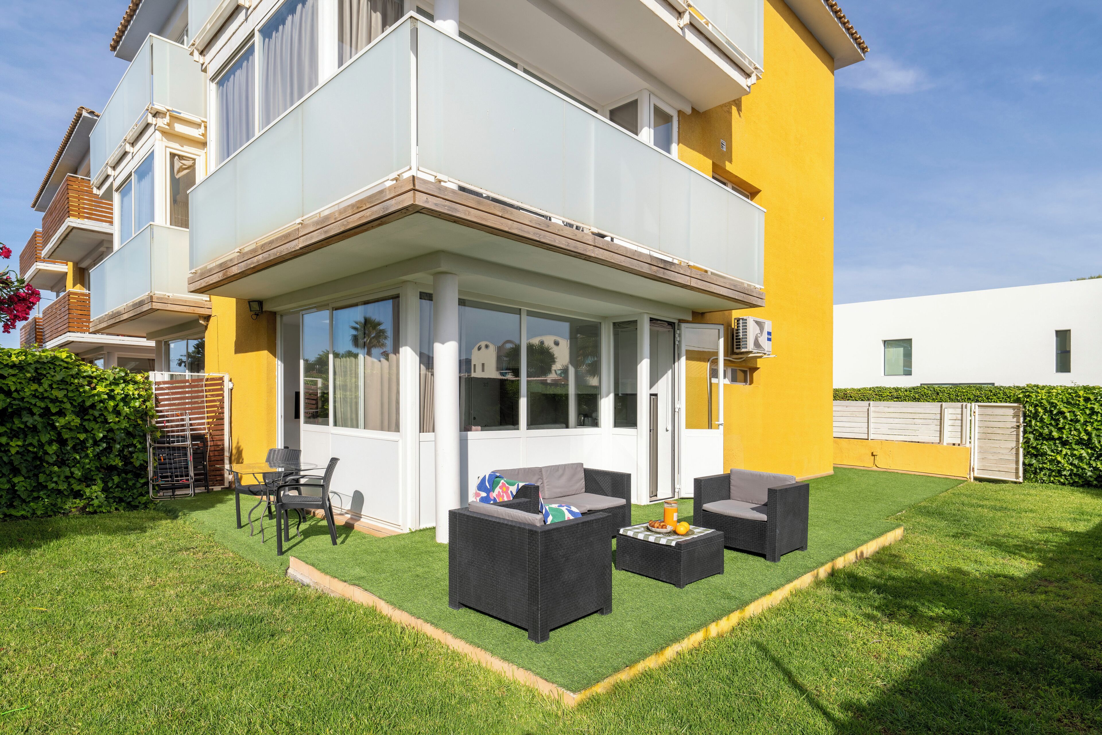 A two-story house with a covered patio, outdoor furniture, and a well-maintained lawn.