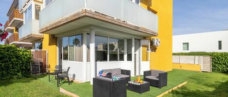A two-story house with a covered patio, outdoor furniture, and a well-maintained lawn.