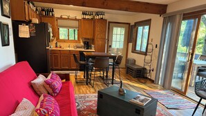 Una sala de estar acogedora con un sofá rojo, una mesa de centro y una zona de cocina con armarios de madera y una mesa de comedor.