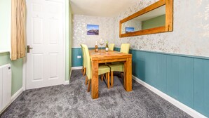 Un coin repas avec une table et des chaises en bois, une porte blanche et un miroir au mur.