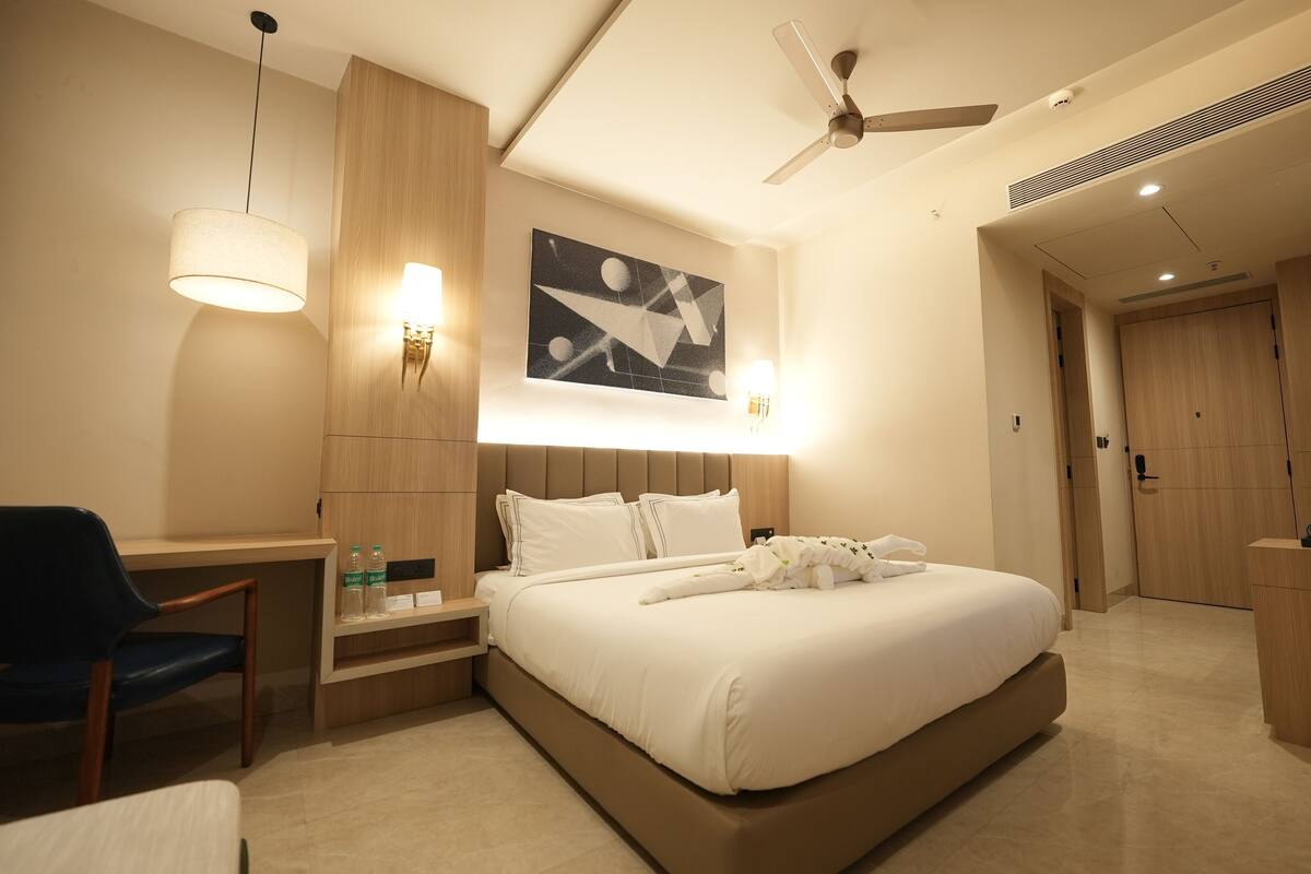 A hotel room with a bed, desk, chair, and a ceiling fan.