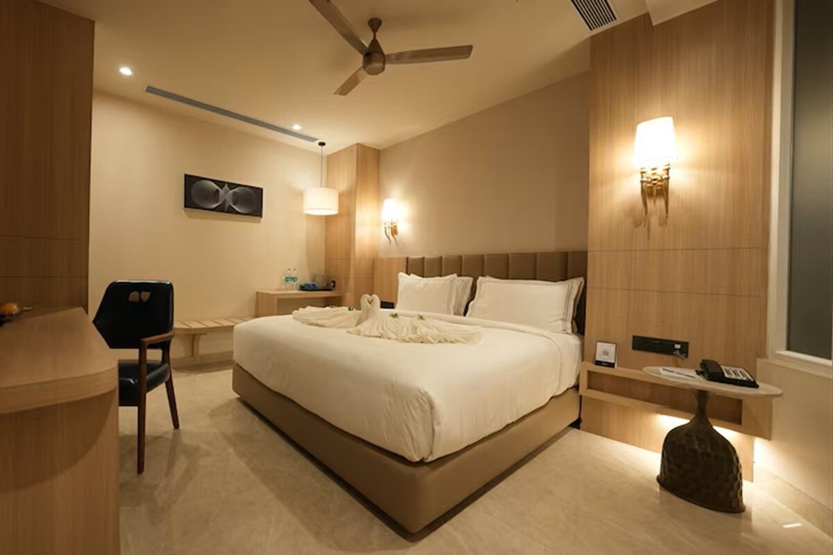 Habitación de hotel moderna con una cama grande, un escritorio, una silla y una mesita de noche con lámpara.