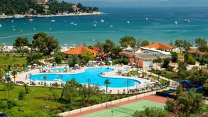 Ein Resort mit großem Schwimmbad, Tennisplätzen und Meerblick.
