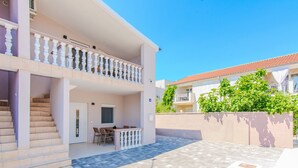A two-story building with a balcony, a staircase, and a patio area with a tiled floor. - Apartments Mucaj (Vir)