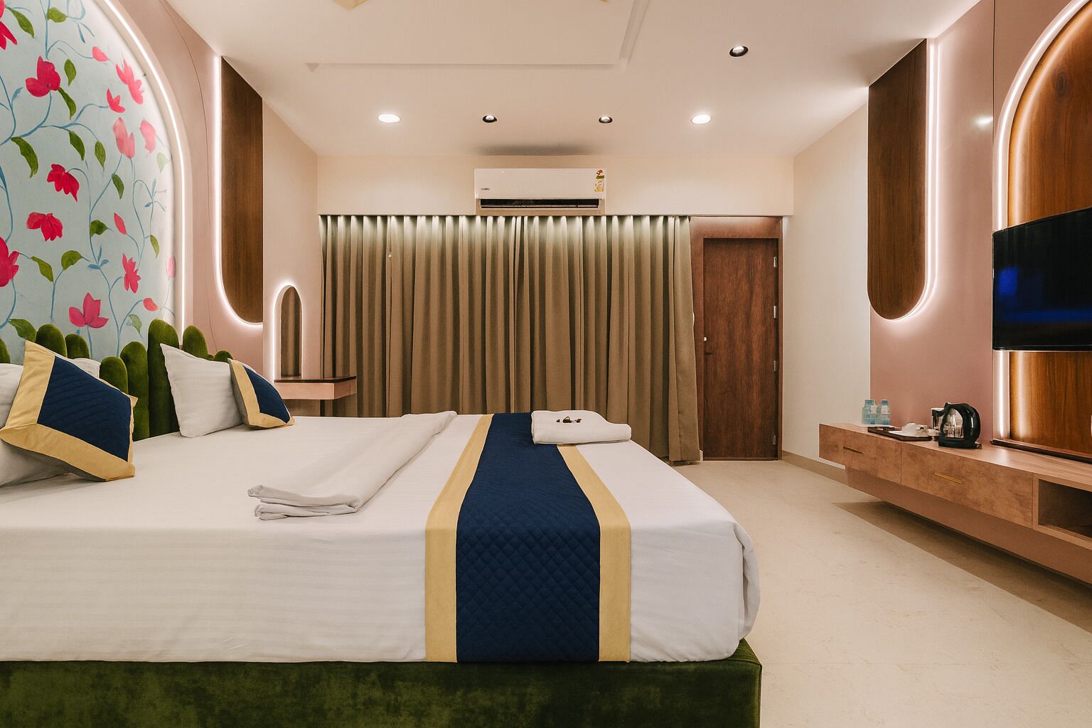 A hotel room with a large bed, a flat-screen TV, a minibar, and a wooden sideboard.