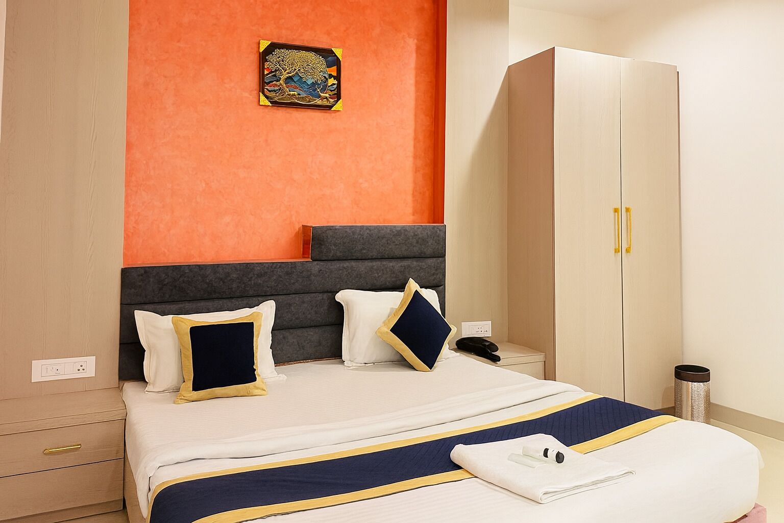 A hotel room with a bed, a wardrobe, and a small table with a phone.