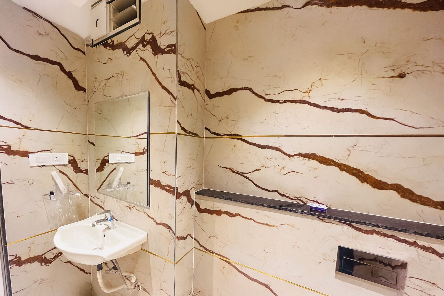 Un baño con un lavamanos blanco, un espejo y una repisa con artículos de tocador.
