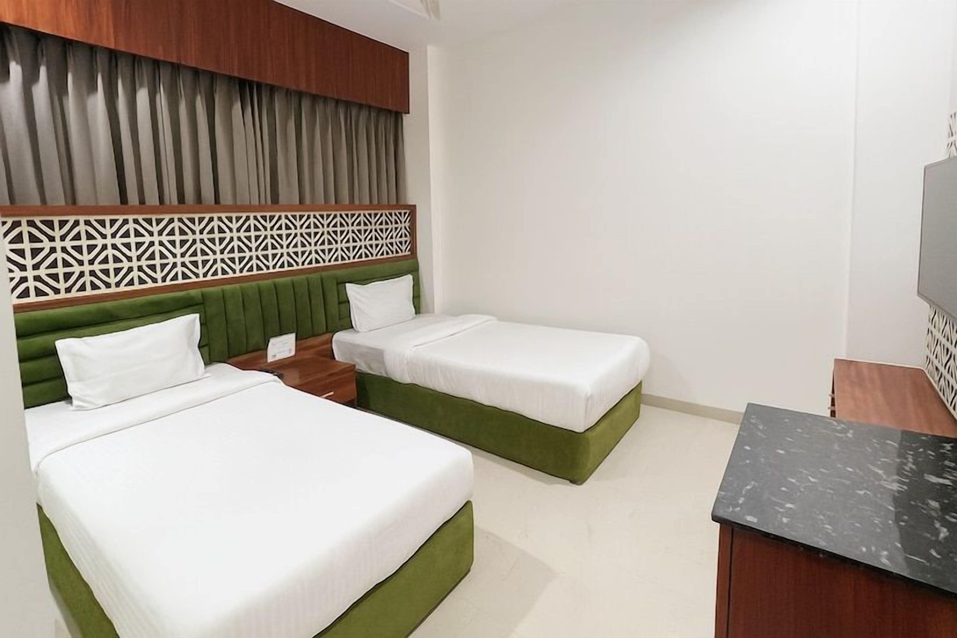 Habitación de hotel con dos camas, cabecero de madera, televisor de pantalla plana y una mesita de madera.