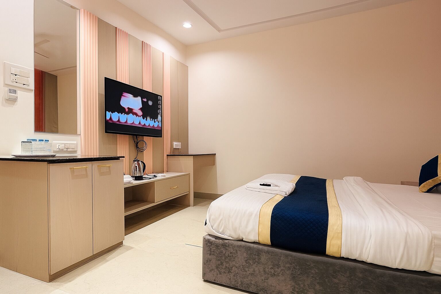 Hotellihuone, jossa on sänky, televisio, työpöytä ja minibaari.