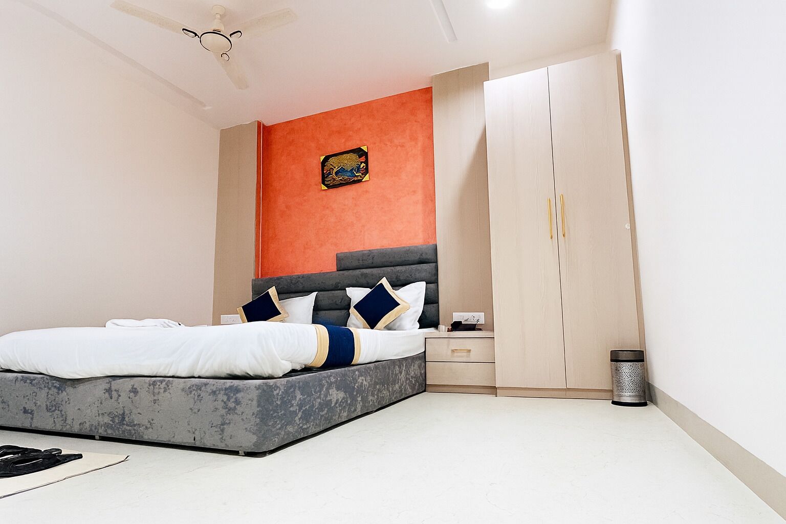 A bedroom with a bed, nightstands, a wardrobe, and a trash can.