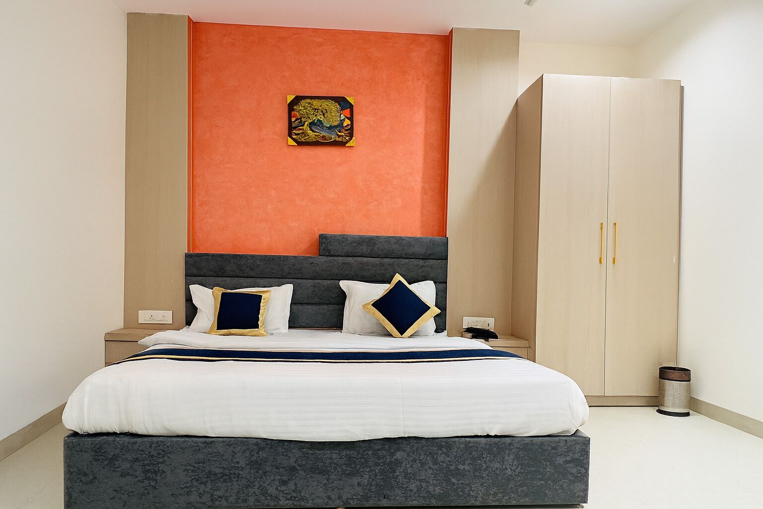 A bedroom with a bed, a wardrobe, and a wall-mounted artwork.
