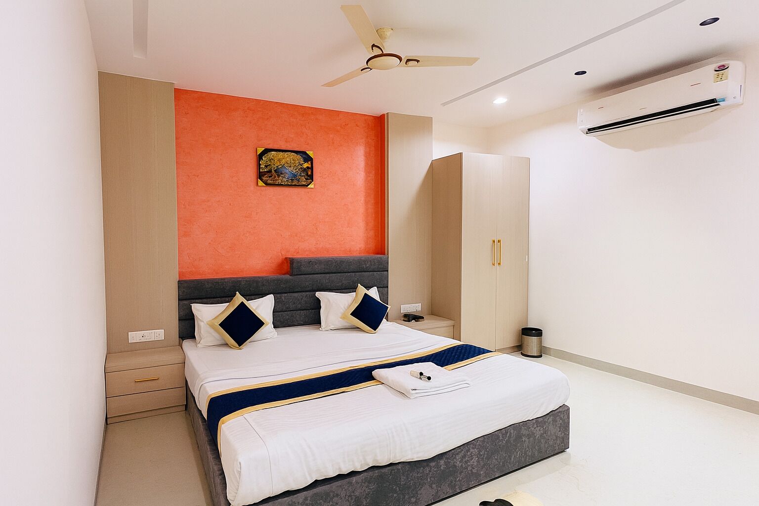 A modern bedroom with a bed, a wardrobe, an air conditioning unit, and a ceiling fan.