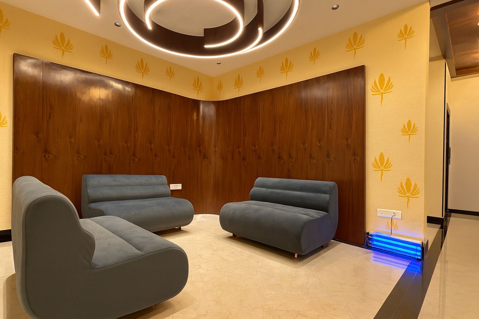 Een moderne kamer met twee grijze banken, houten paneelwanden en een plafondlamp.