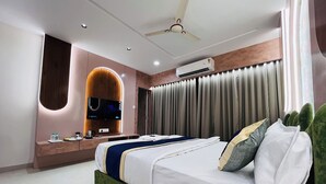 A modern hotel room with a large bed, a TV mounted on a wooden wall, an air conditioning unit, and a ceiling fan. - HOTEL HILL PARK (Indore)