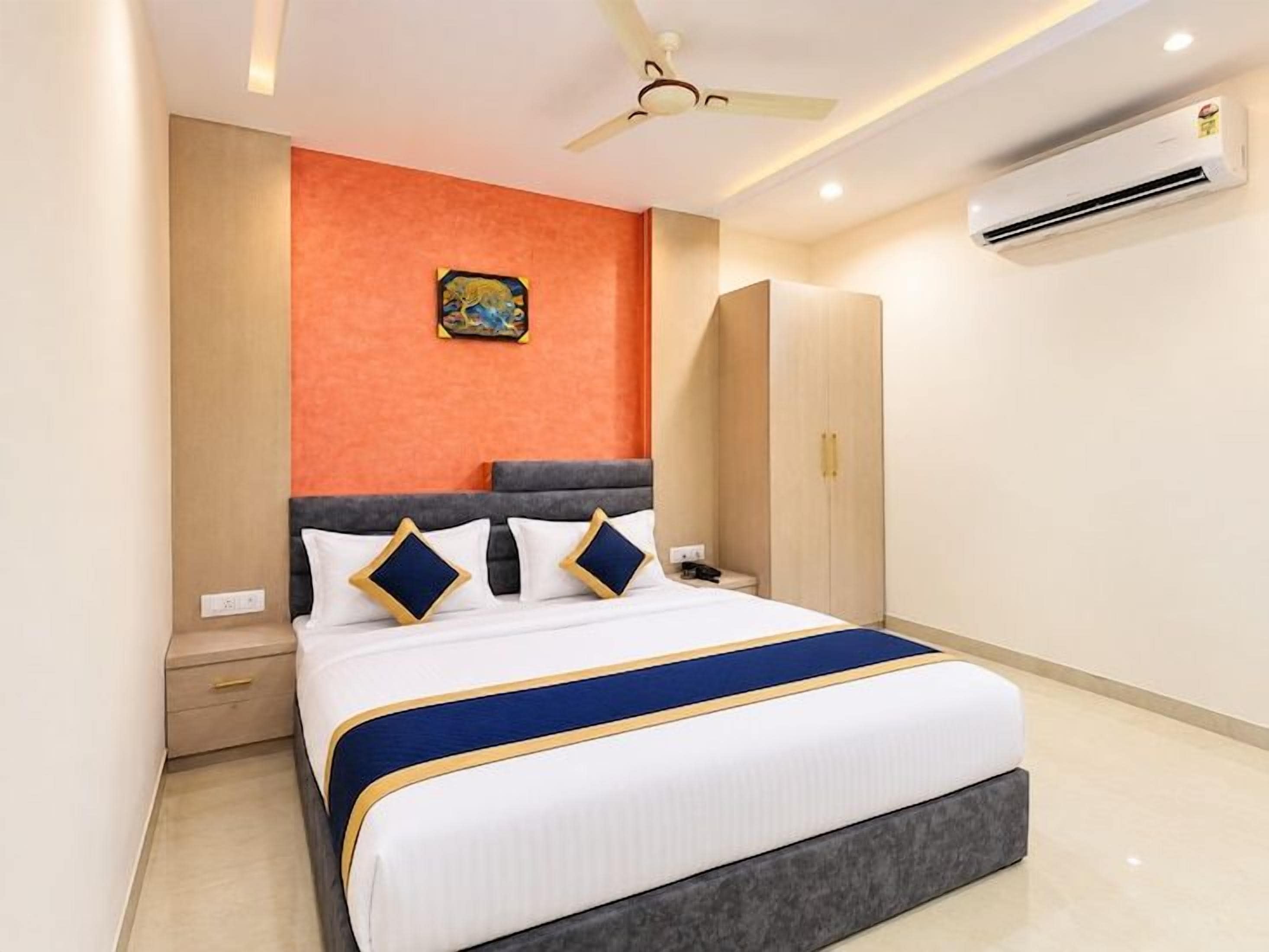 Una habitación de hotel moderna con cama, mesita de noche, armario y ventilador de techo.