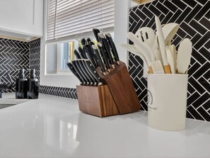 Una cocina con un bloque de cuchillos, un recipiente para utensilios y un salpicadero.