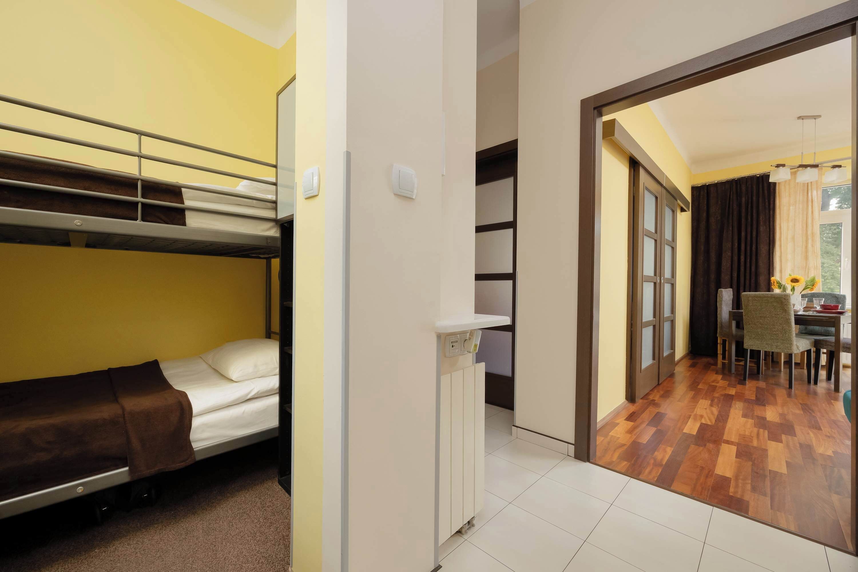 Ein Hotelzimmer mit Stockbetten, einem Schreibtisch, einem Stuhl und einer Essecke mit Tisch und Stühlen.