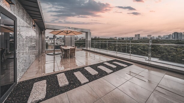 Une terrasse sur le toit comprenant un espace repas, une vue sur les toits de la ville et une rambarde en verre.