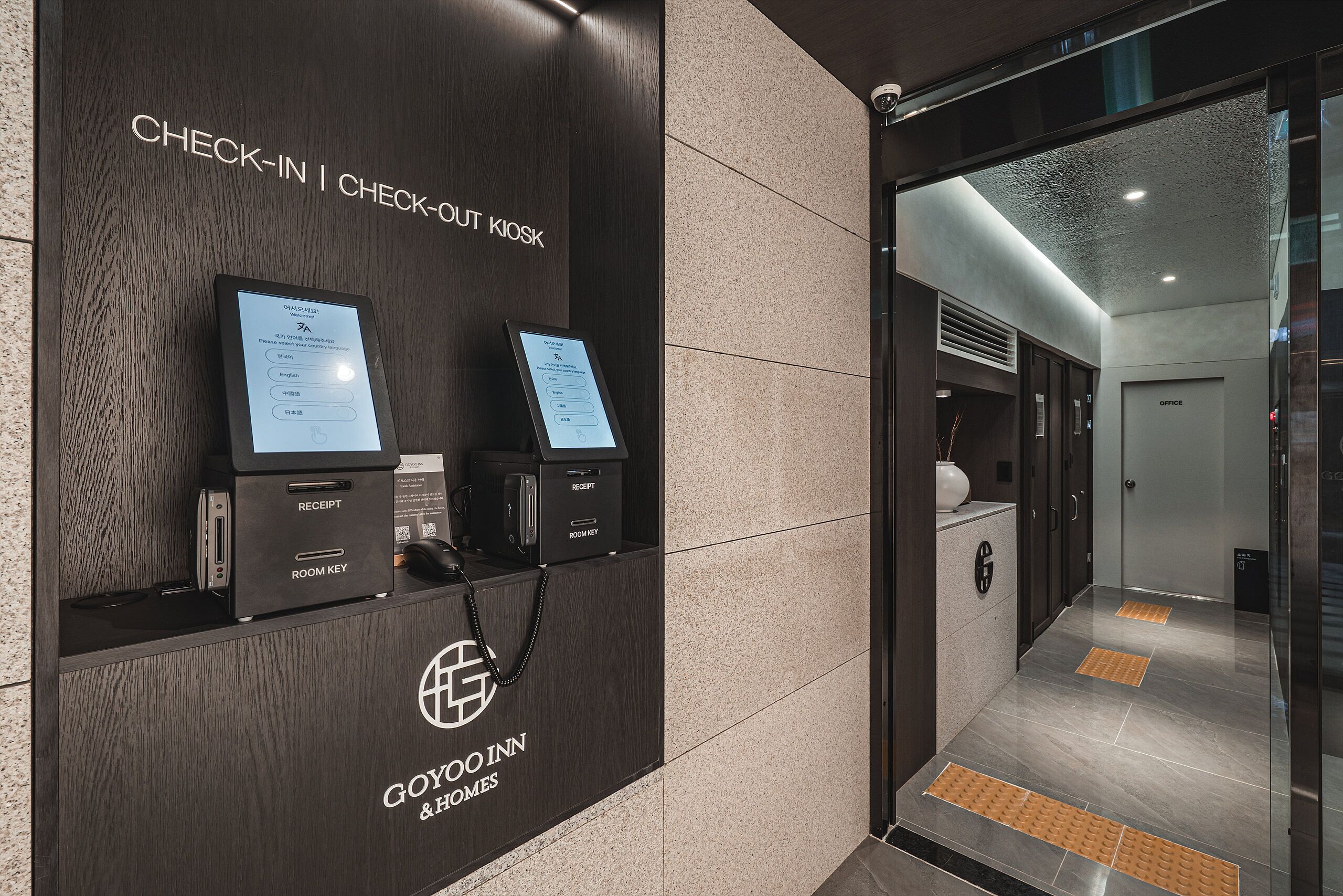 A reception desk with a check-in/out kiosk, a reception area, and a hallway leading to an office.