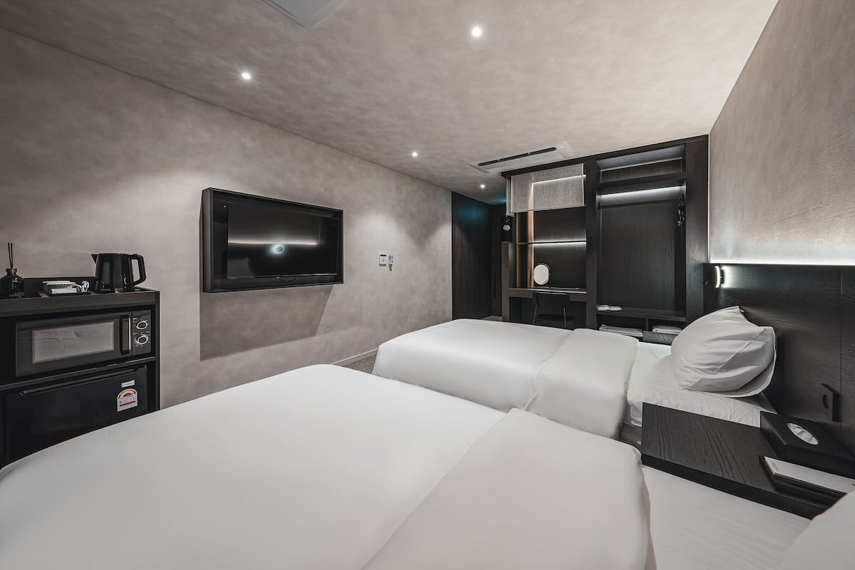 A modern hotel room with a large bed, a television, a minibar, and a mirror.