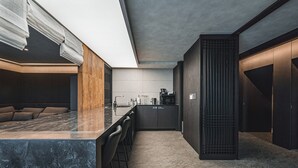 Une cuisine moderne dotée d’un plan de travail en marbre, de tabourets de bar et d’un four encastré.
