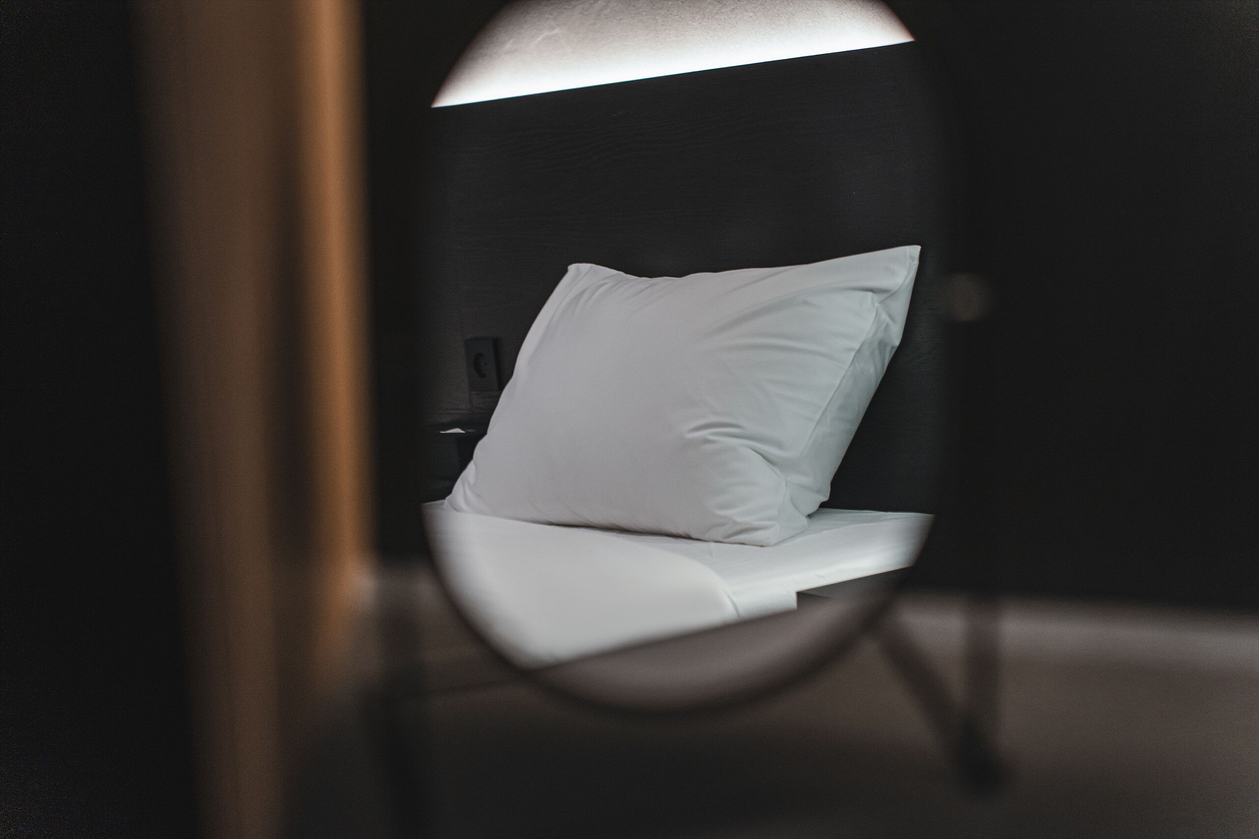 A bed with white bedding in a dimly lit room.