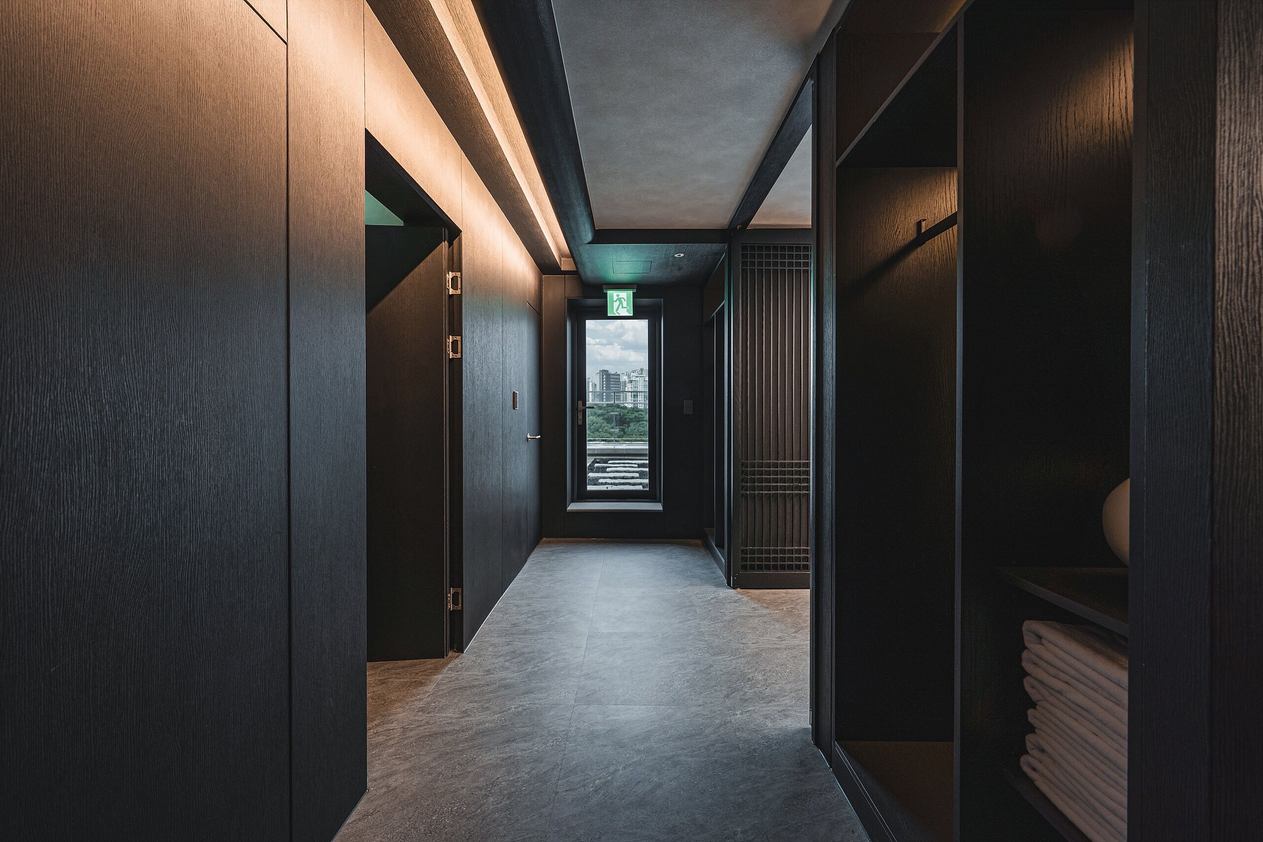 A modern hallway with a view of a cityscape through a window.