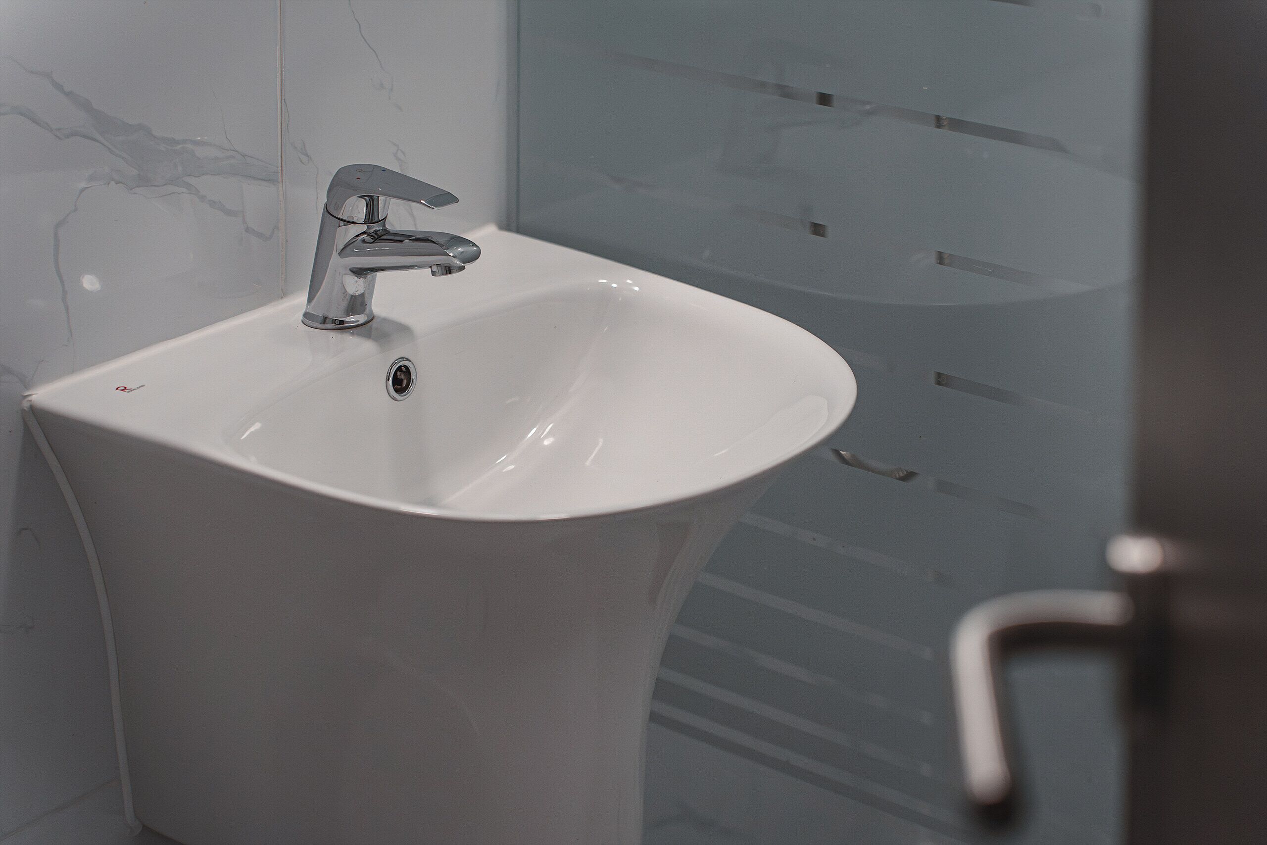 A bathroom sink with a modern faucet, a mirror, and a glass shower enclosure.