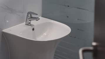 A bathroom sink with a modern faucet, a mirror, and a glass shower enclosure.