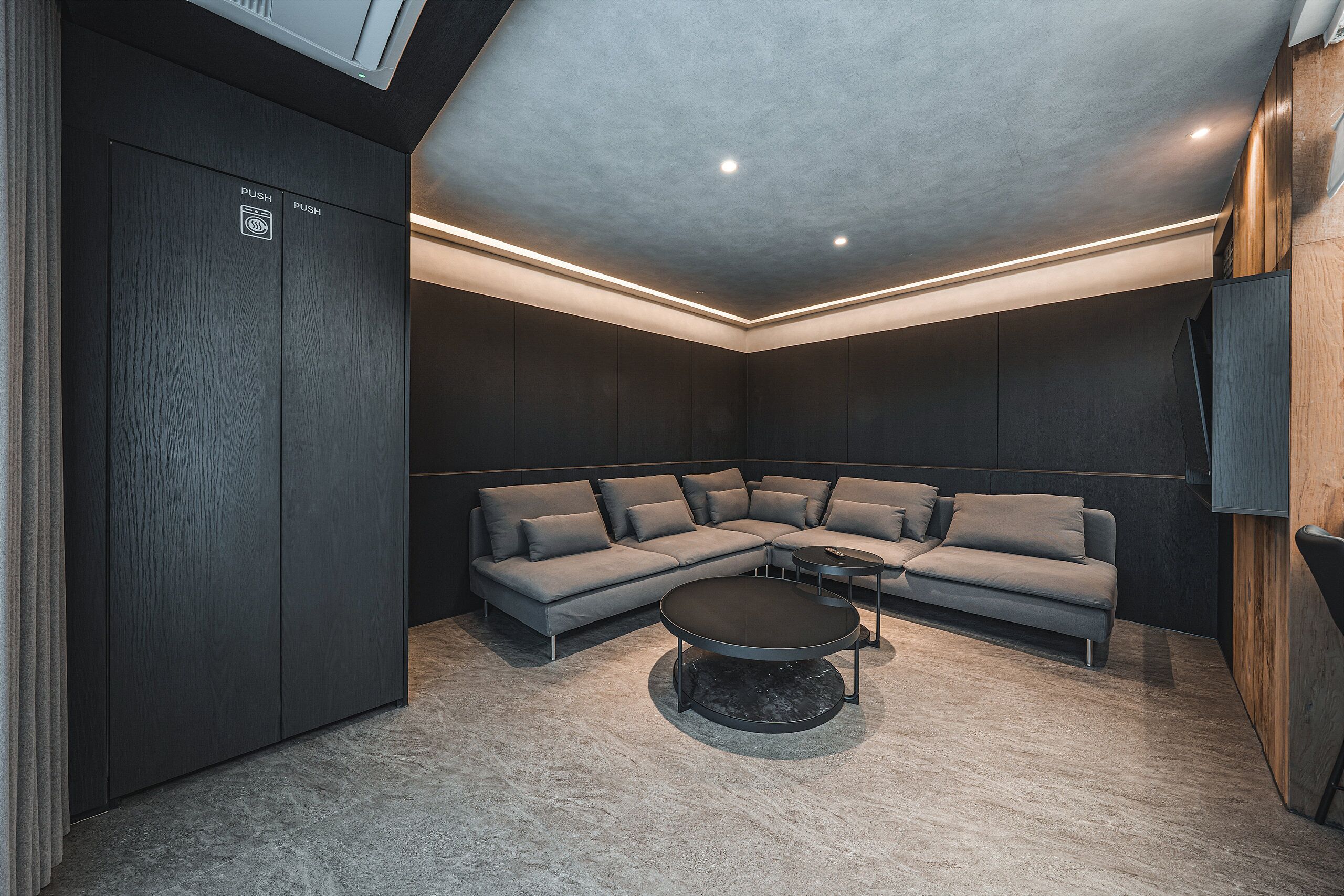 Una sala moderna con un sofá modular, una mesa de centro redonda e iluminación empotrada en el techo.