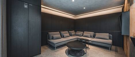 Una sala moderna con un sofá modular, una mesa de centro redonda e iluminación empotrada en el techo.
