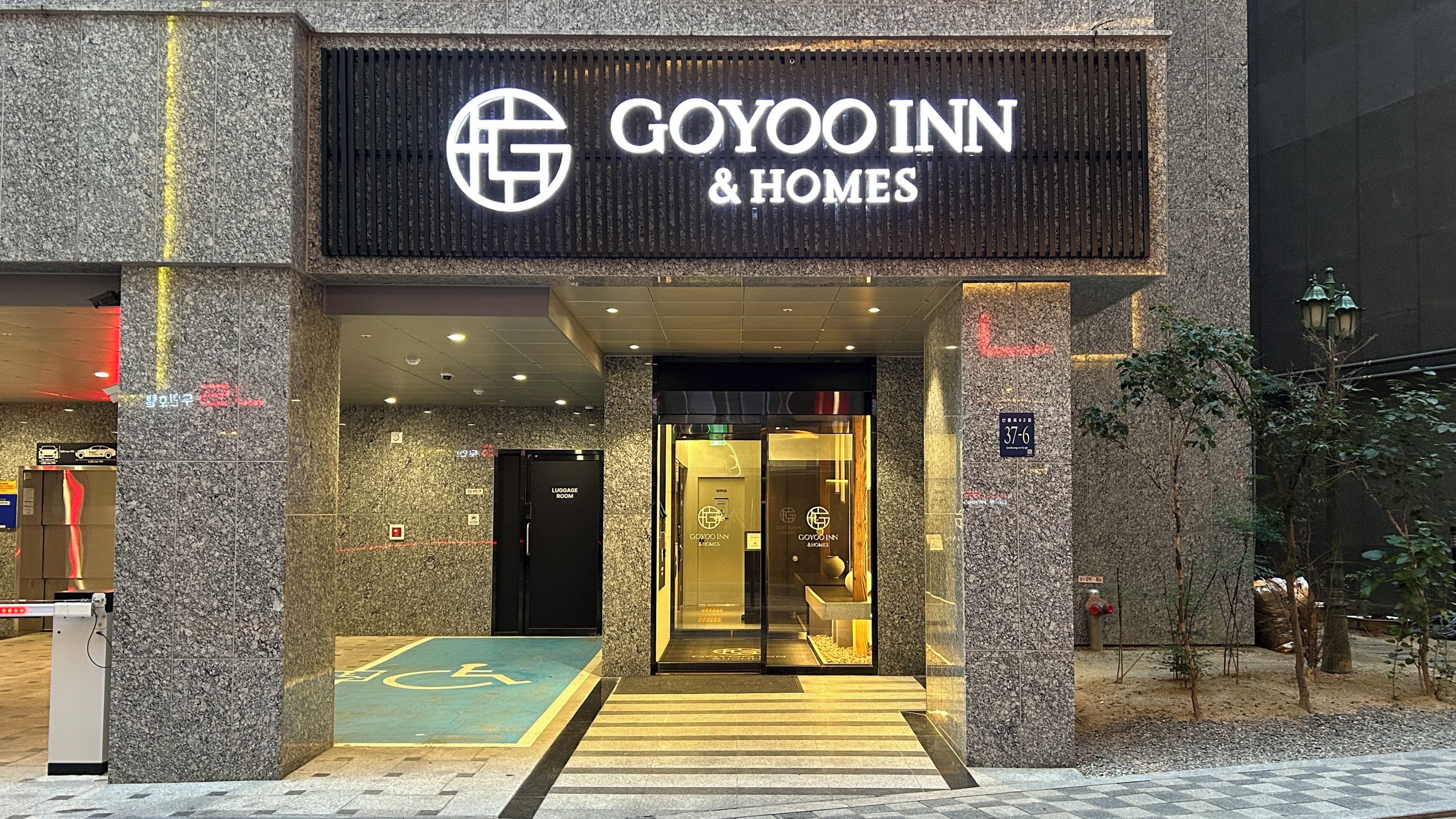 A hotel entrance with a prominent sign for Goyoo Inn & Homes, a luggage room, and a handicapped accessible entrance.