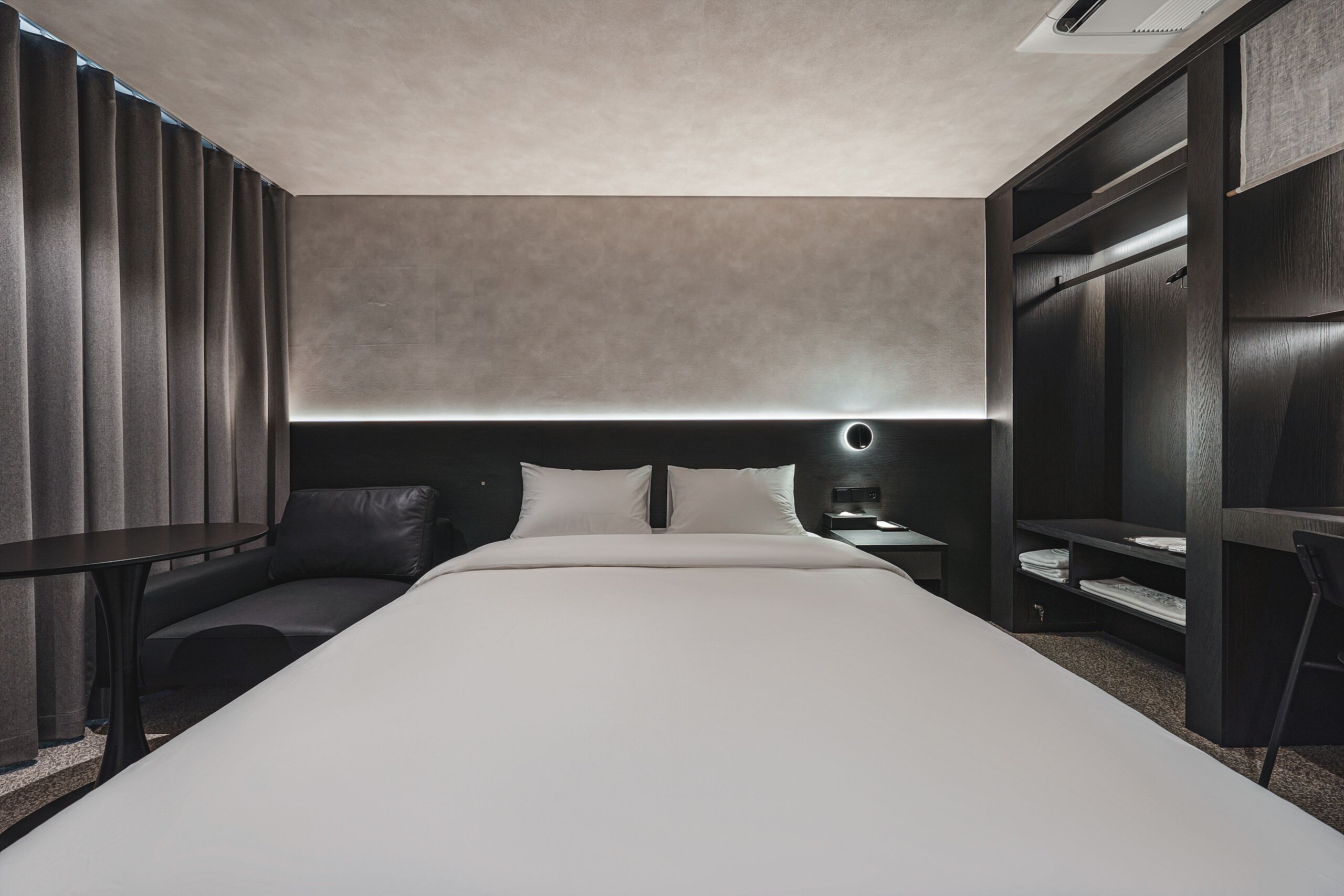 Et moderne hotelværelse med en stor seng, et natbord og indbyggede hylder.