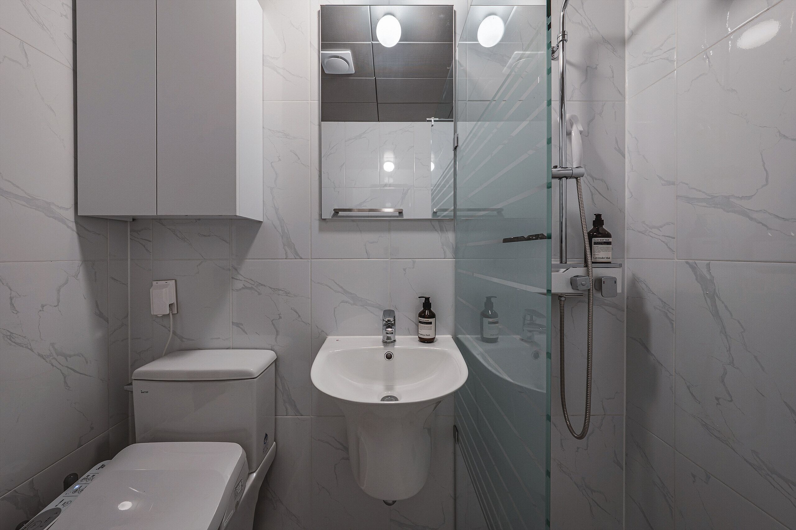 A modern bathroom with a toilet, sink, and shower.