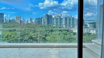 A balcony with a cityscape view, including high-rise buildings and greenery.