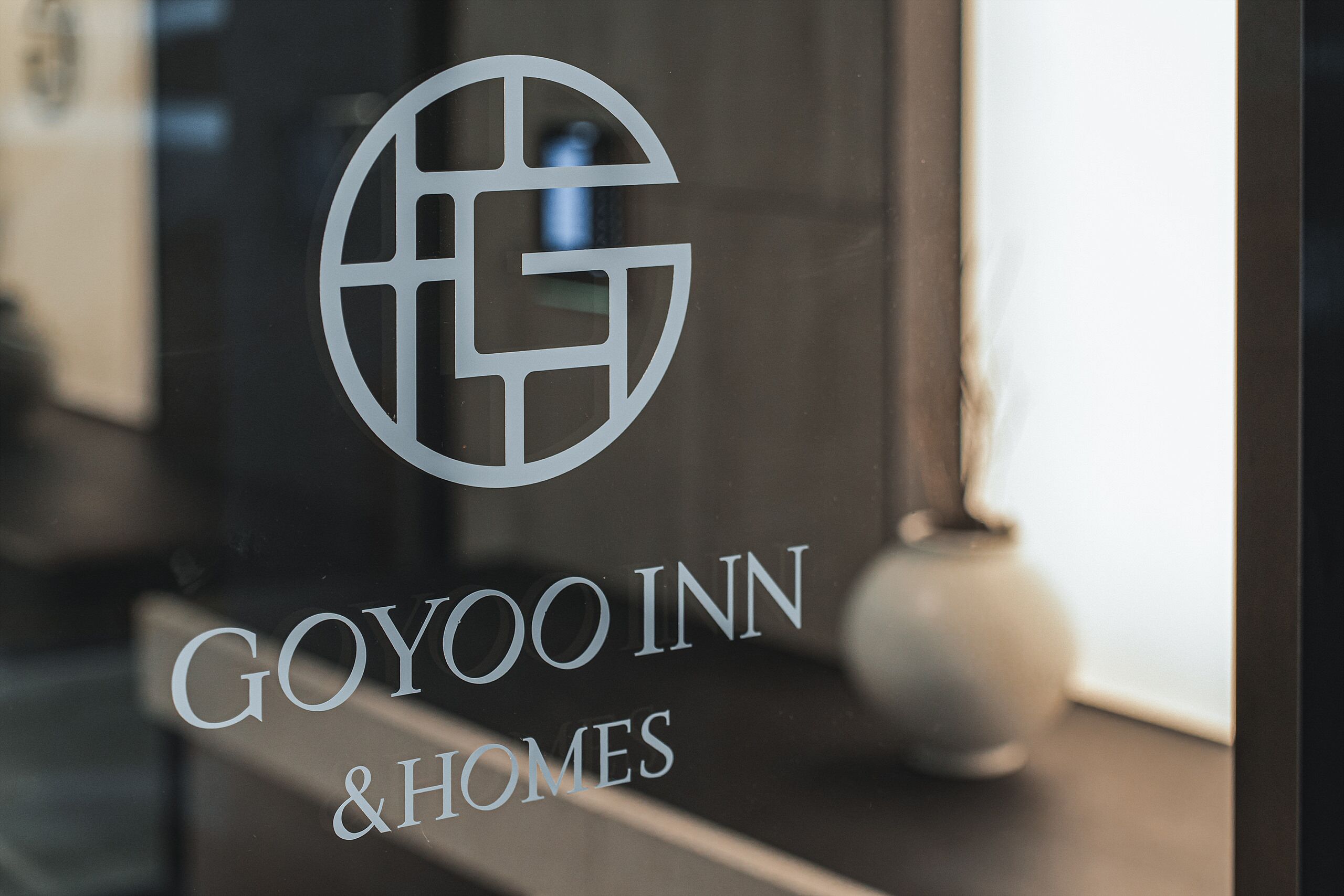 Lasiruudussa on näkyvissä yrityksen ”Goyoo Inn & Homes” logo ja nimi.