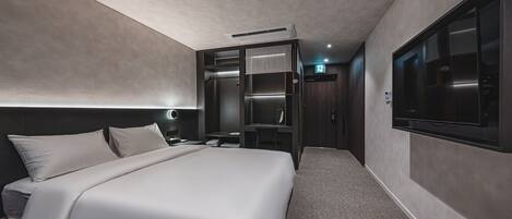 Une chambre d’hôtel moderne dotée d’un grand lit, d’un placard intégré, d’une table de chevet et d’un téléviseur fixé au mur.