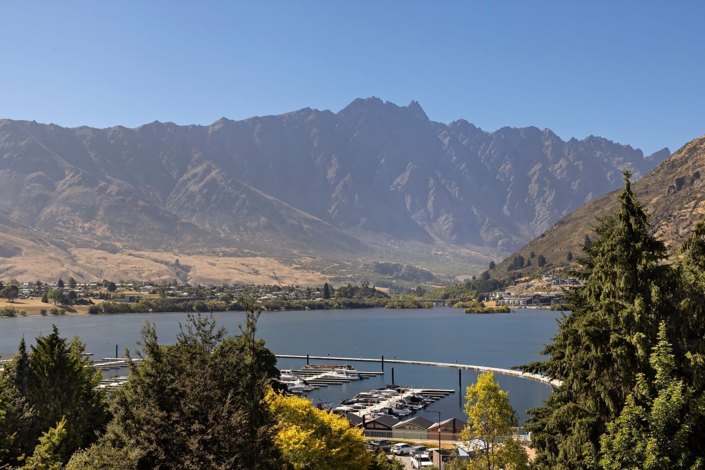 A marina with boats docked, surrounded by mountains and a clear sky.