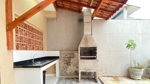 Un patio con una parrilla integrada y piso de baldosas.