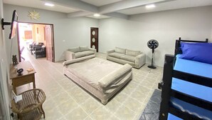 Un dormitorio con cama, sofá, escritorio y ventilador.