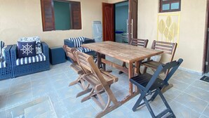 Un comedor con una mesa y sillas de madera, un sofá con cojines a rayas y suelo de baldosas.